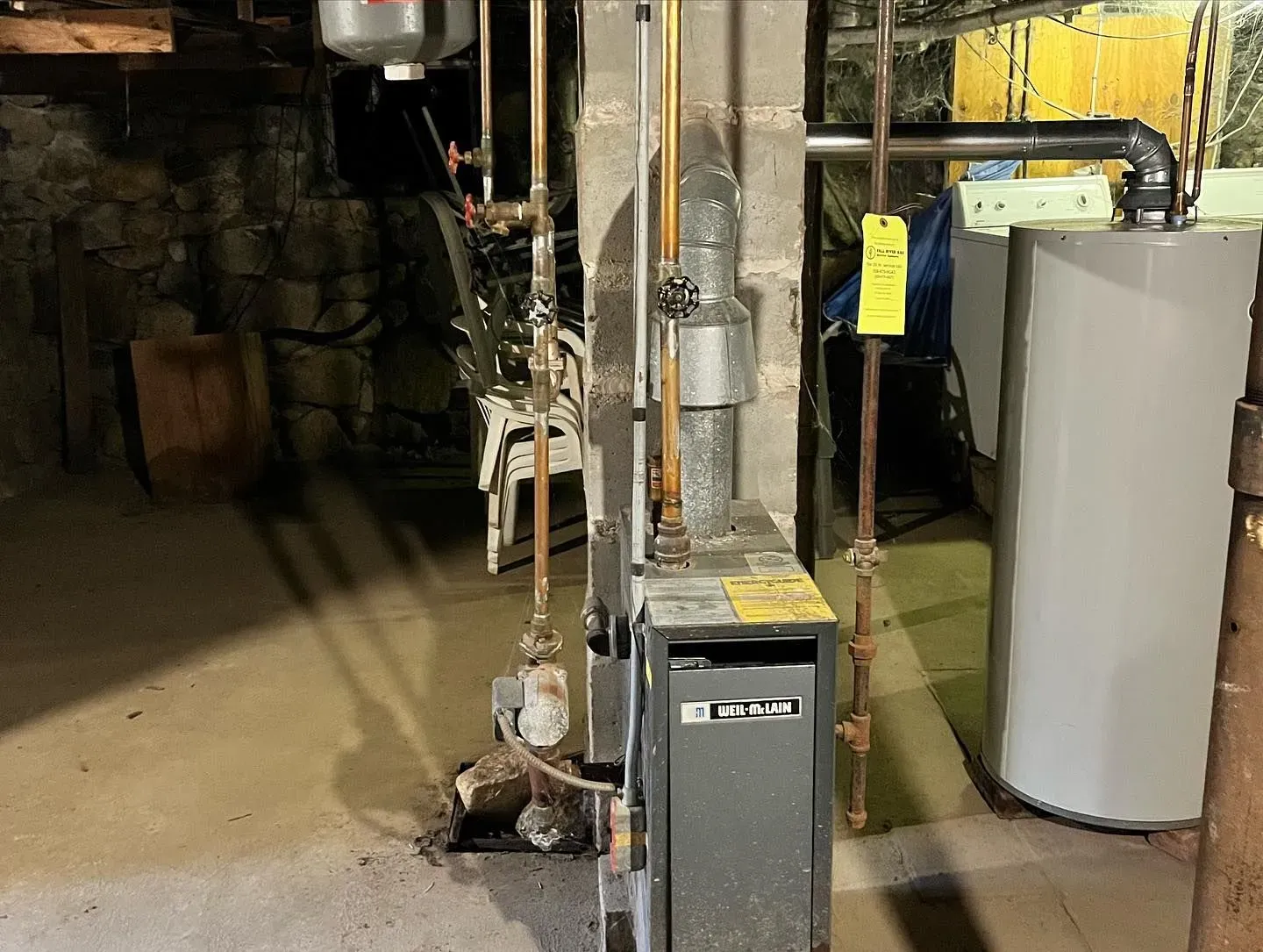 A boiler and a water heater are in a basement.