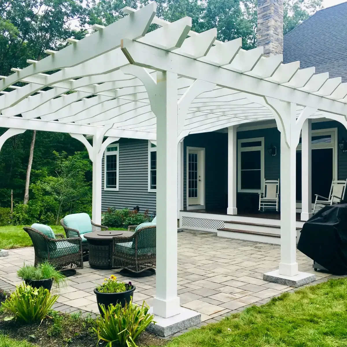 Wooden arbor over a paver patio and built-in grill island featuring granite countertops