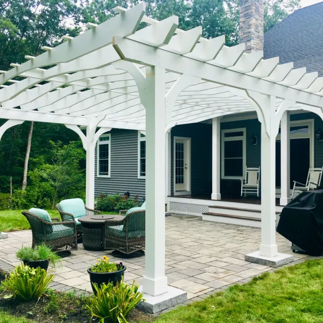 Wooden arbor over a paver patio and built-in grill island featuring granite countertops
