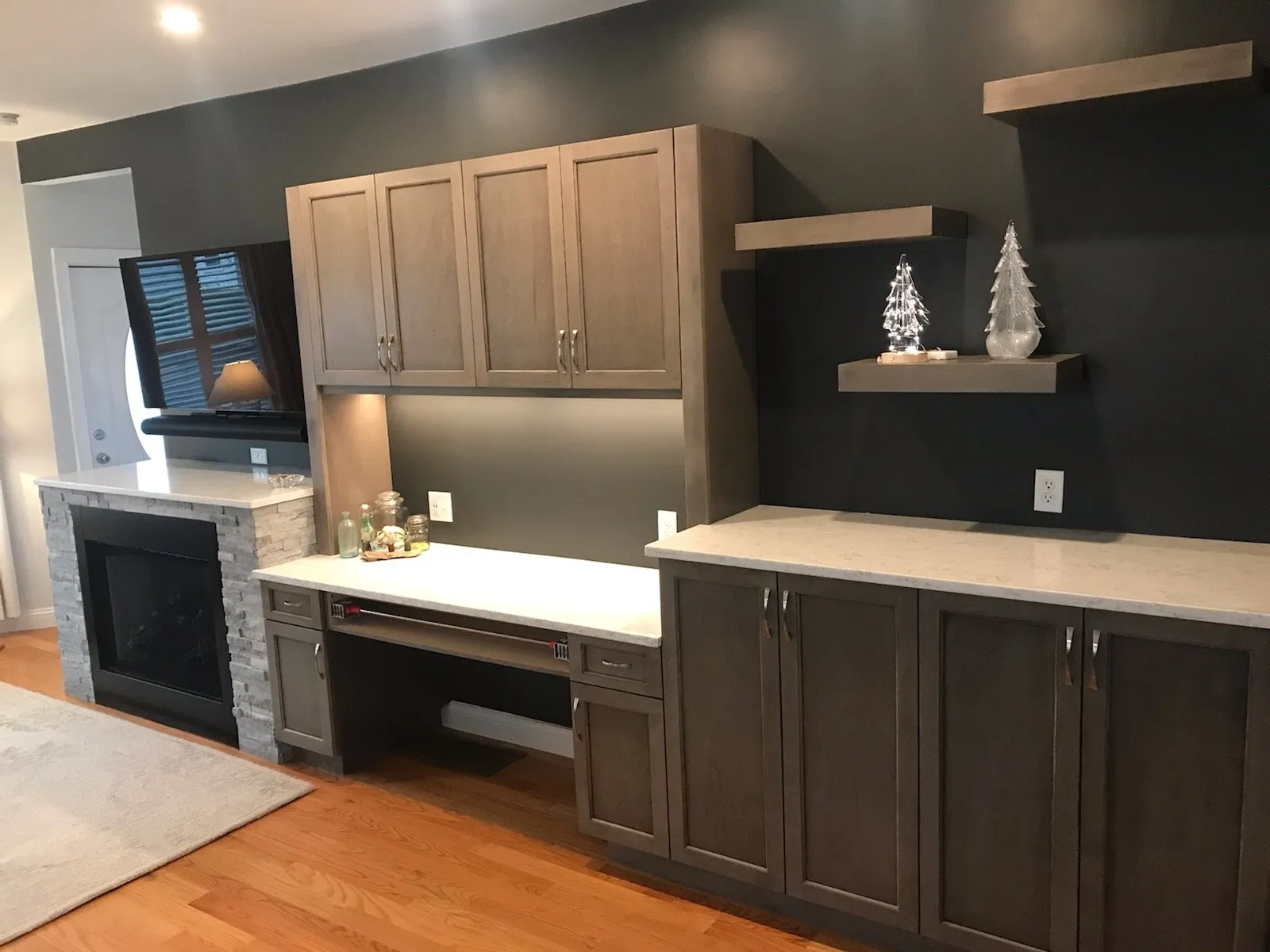 Built-in desk and cabinetry beside a tiled fireplace