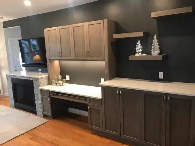 Built-in desk and cabinetry beside a tiled fireplace