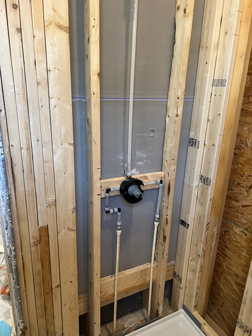 Shower before renovation with open framing and older materials