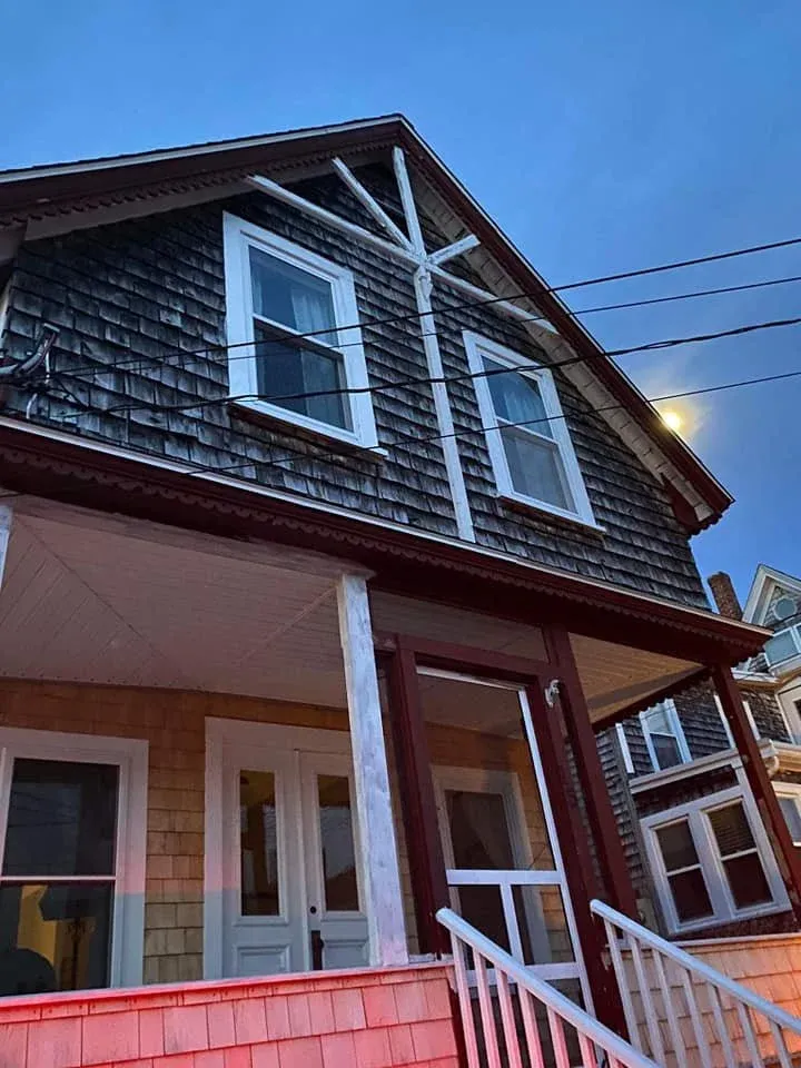 Before, the front of a cottage/small home, with real wooden shingling, dirty and in need of a clean.