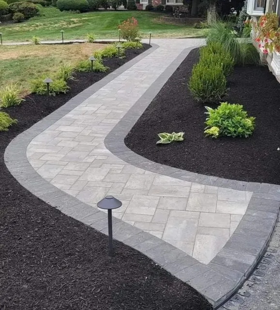 A stone path leading to a yellow house in a garden.