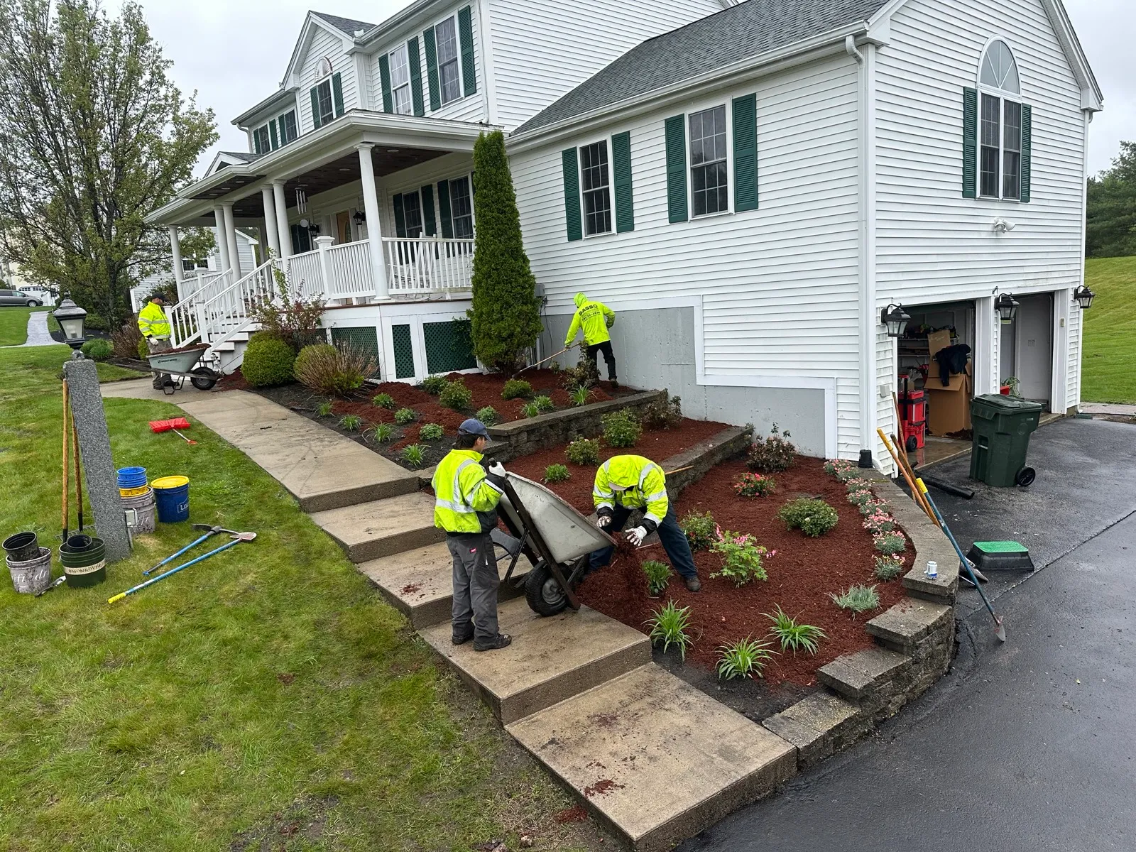 Sasso crew in hi-vis spreading fresh mulch and refreshing the front-yard beds of a residential property