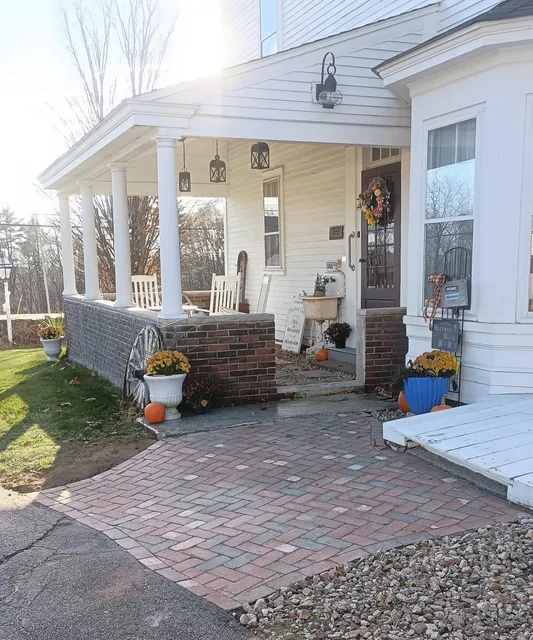 A herringbone brick walkway leading to a covered farmhouse porch