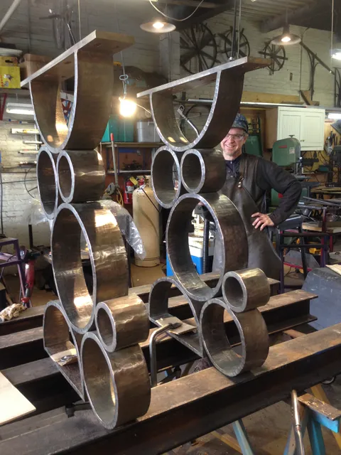 Forged handrail bracket parts laid out on a full-size drawing in the shop