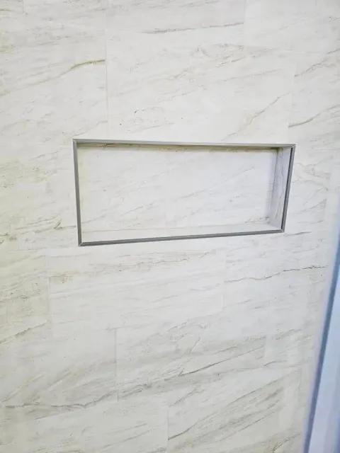 a white tile wall with a shelf in it .