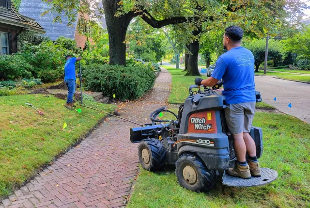 A man is riding a lawn mower down a sidewalk.