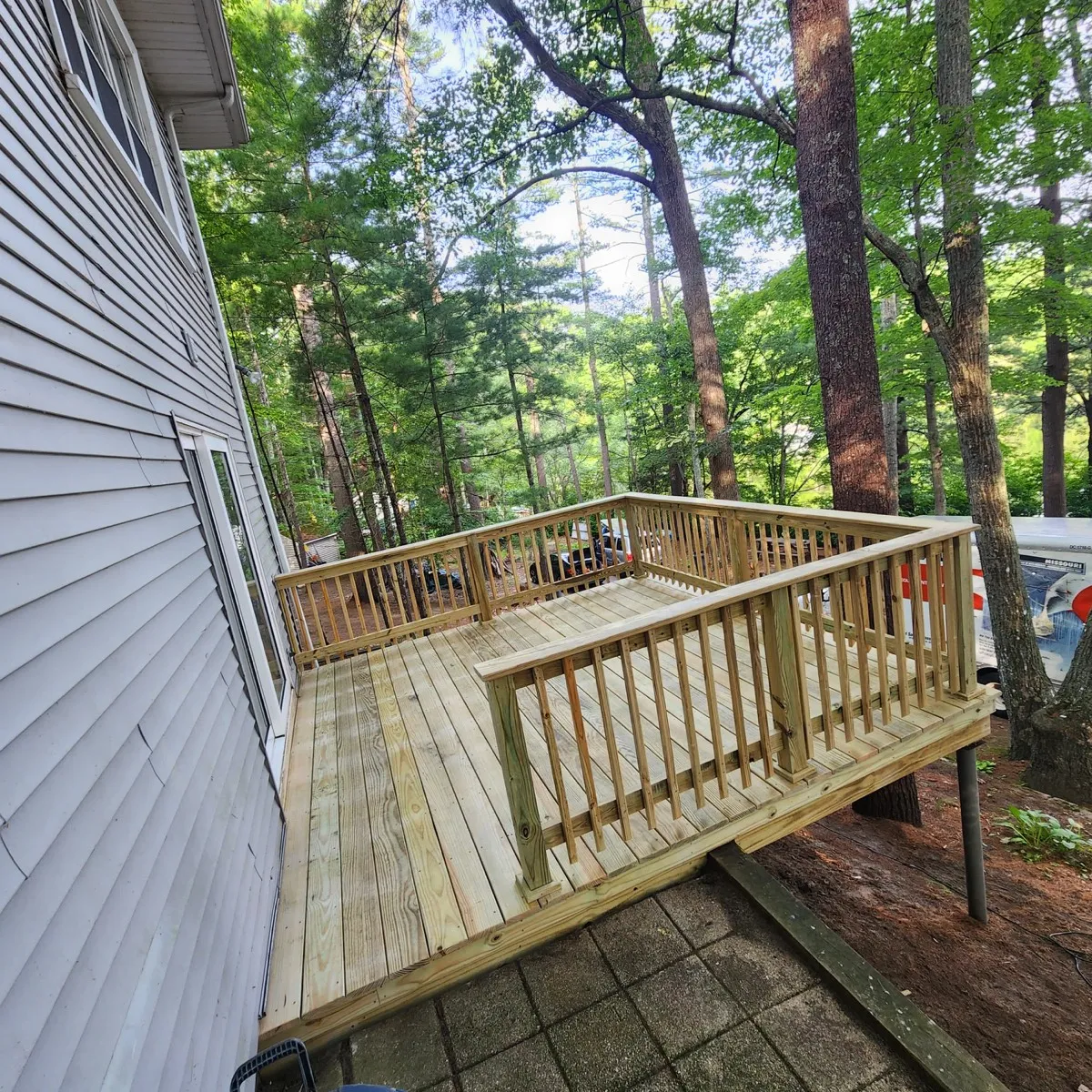 Backyard deck with wood railings surrounded by trees