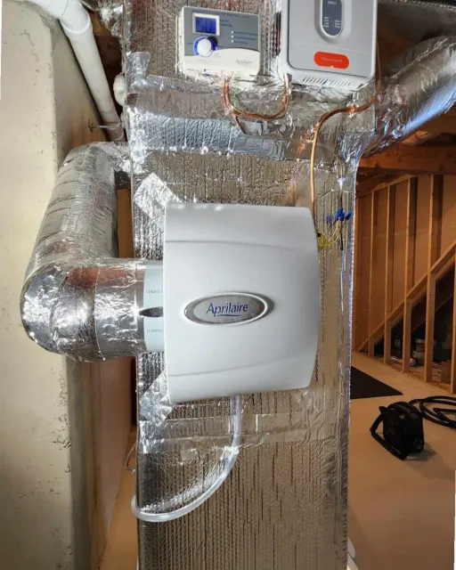 HVAC system installation with insulated ductwork, a central control unit, and wiring, in a construction setting.