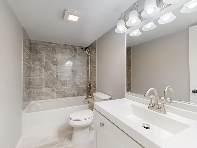 Elegant modern bathroom featuring marble tiles and sleek white vanity.