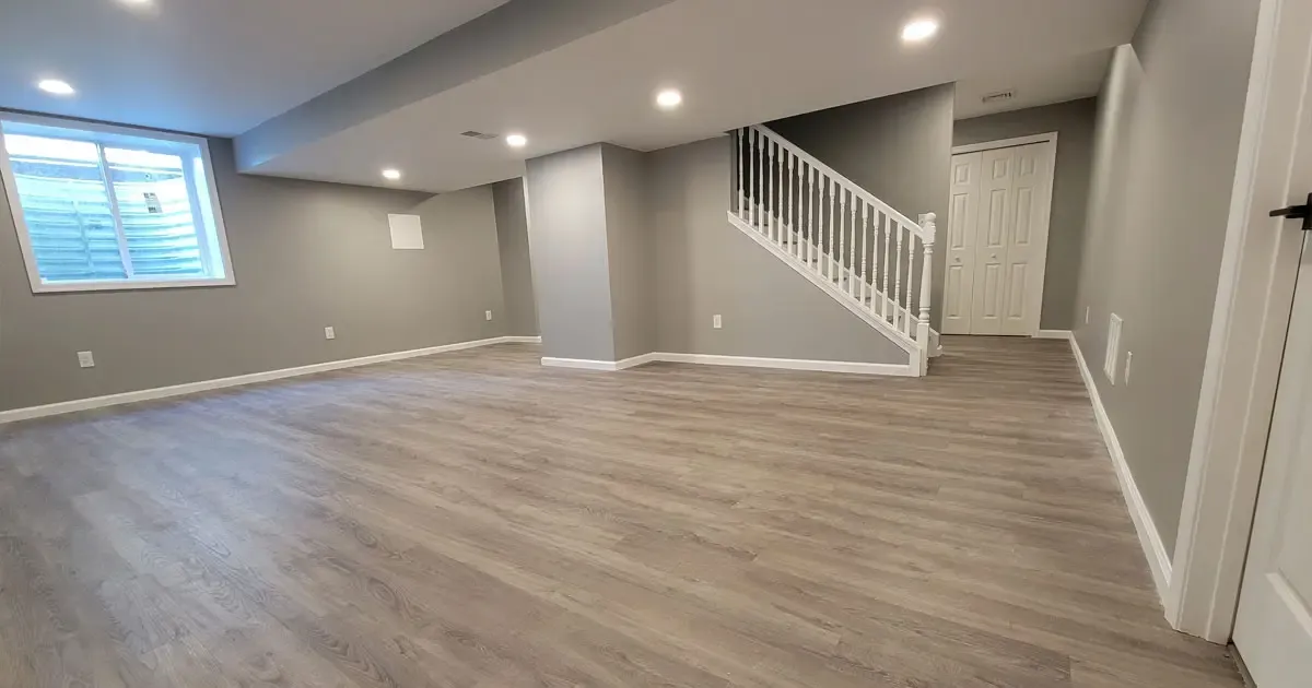 Finished basement with wood flooring, white staircase railing, recessed lighting, and an egress window
