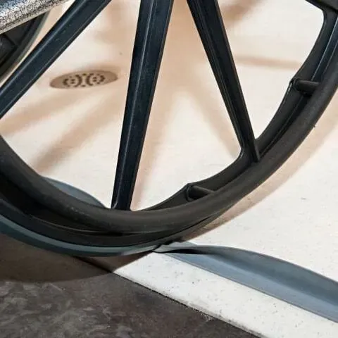 Close-up of a wheelchair wheel rolling over a floor threshold ramp