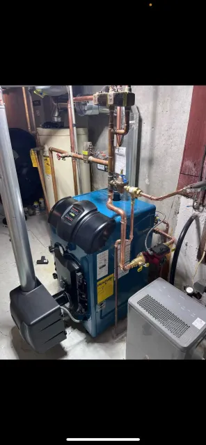 Basement heating equipment with a circulator pump and copper supply and return lines.