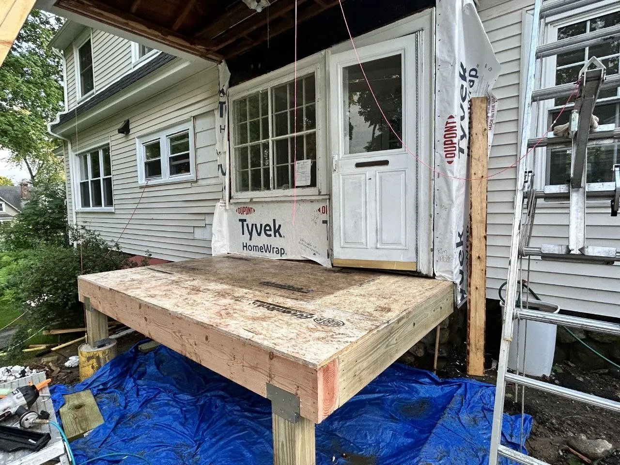 Before: the same addition mid-build, subfloor framed and the wall wrapped in house wrap