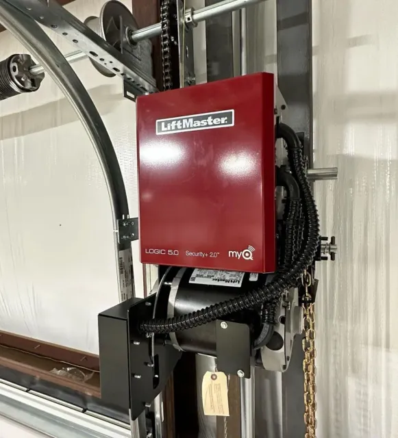 A red liftmaster garage door opener is sitting on top of a garage door