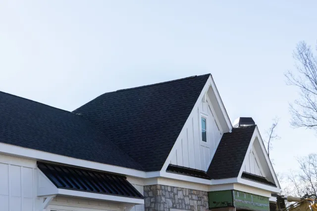 A white house with a black roof and a green awning.
