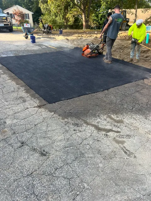 A group of men are working on a driveway.