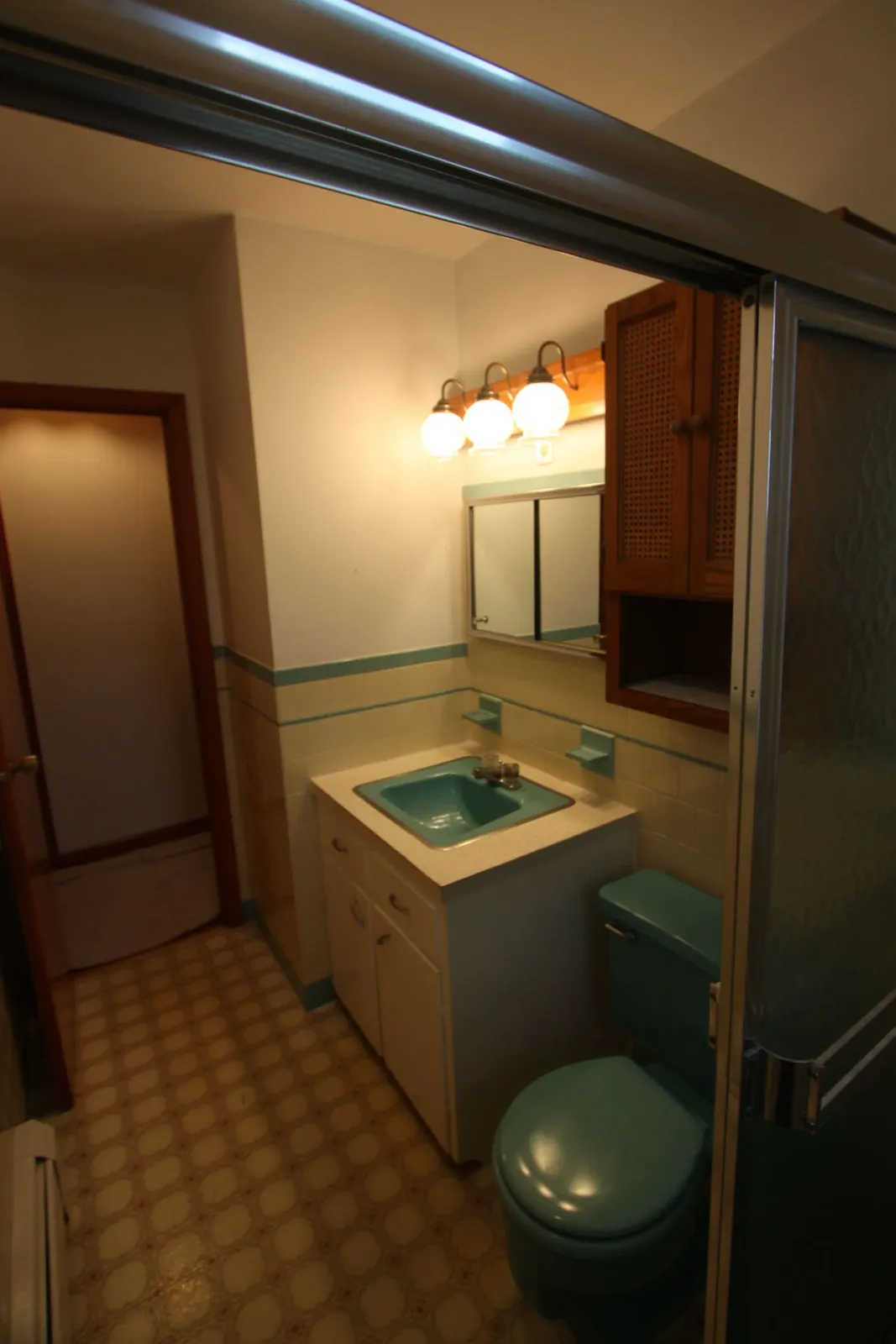 A bathroom with a toilet, a sink, and a mirror.