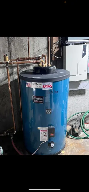 A water heater and adjacent tank in a basement, connected and running.