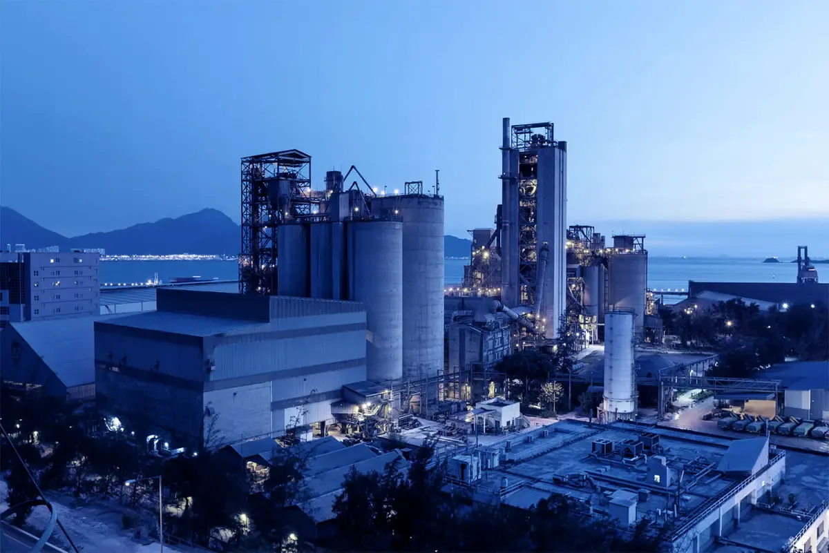 Industrial manufacturing facility illuminated at dusk with floodlights across the plant structures
