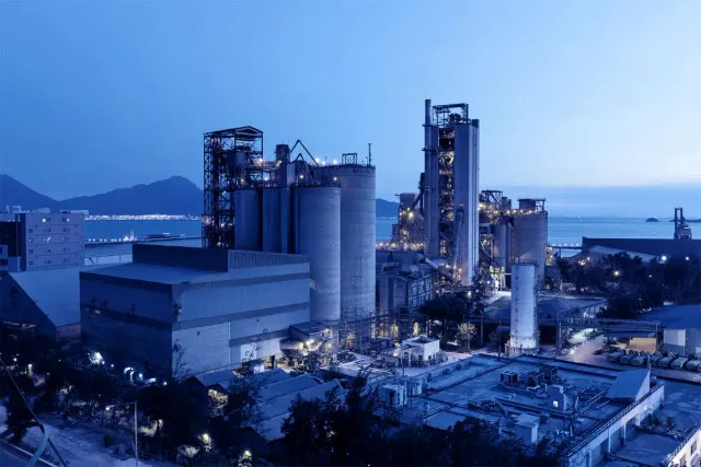 Industrial manufacturing facility illuminated at dusk with floodlights across the plant structures