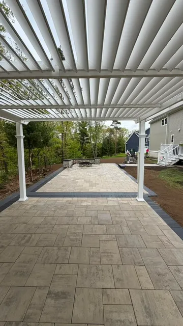 Large paver patio covered by a white pergola with adjustable louvers