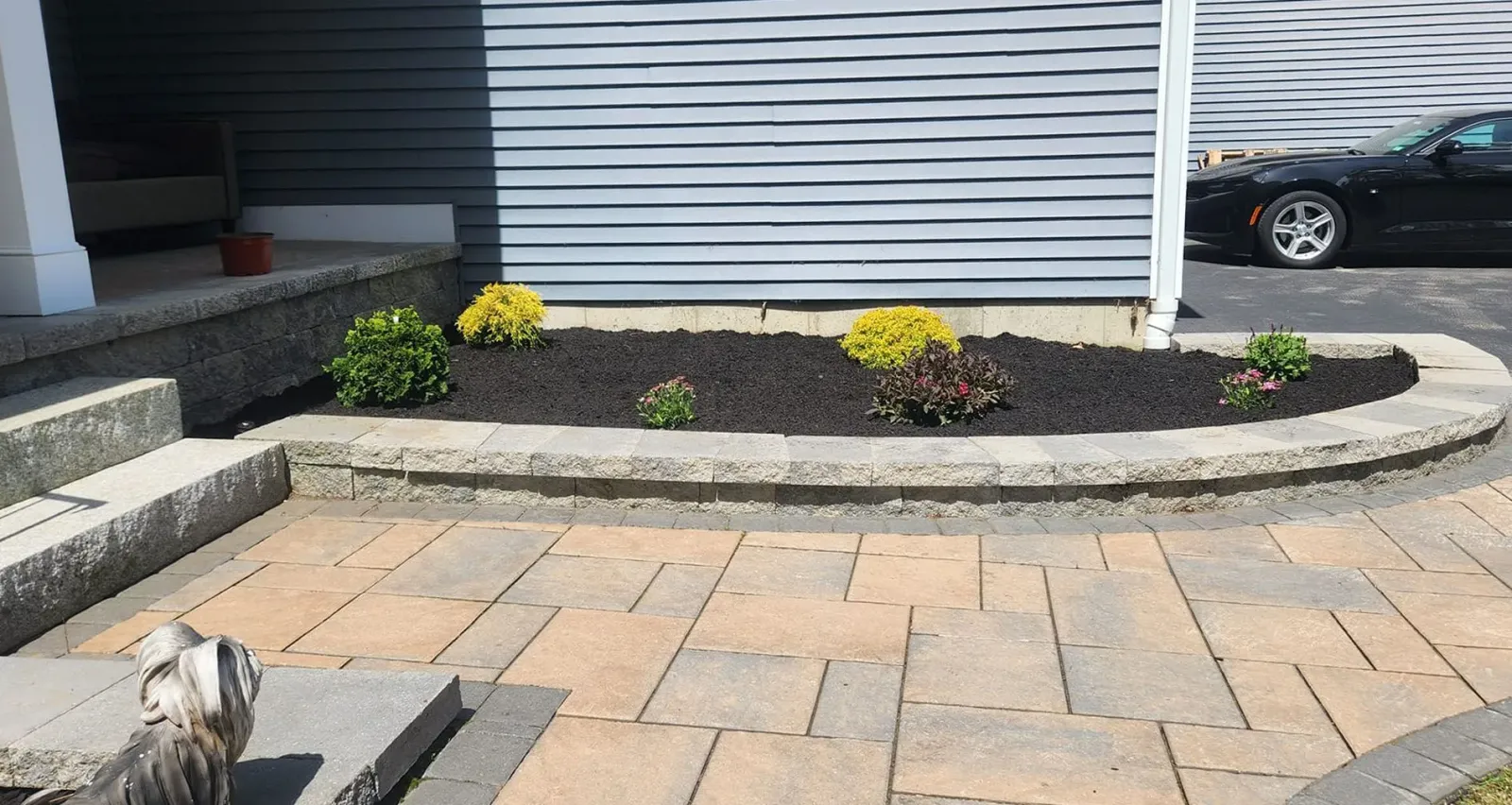 a black car is parked in front of a house with a patio in front of it
