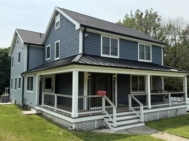 New custom home with a wraparound porch and a standing seam metal roof