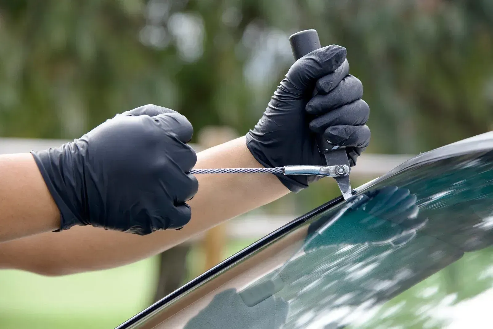 Technician using a windshield removal tool during mobile auto glass service