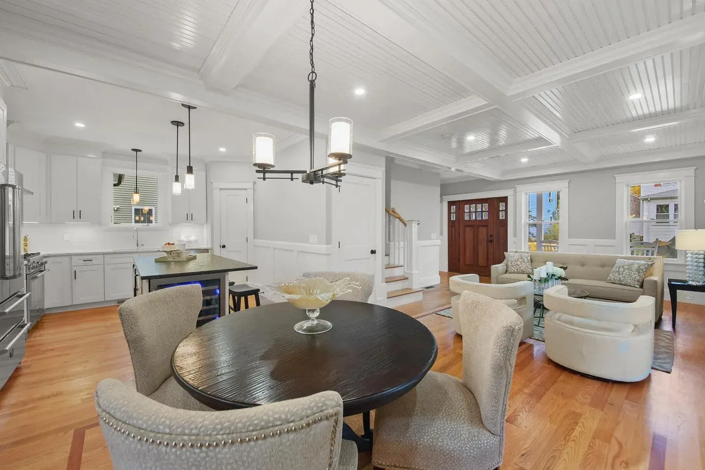 Open room with a coffered ceiling, fitted wall panels and the staircase visible beyond