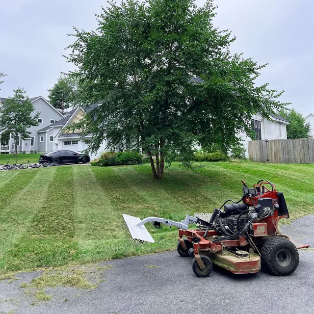 A picture of a lawn mower with a lawn aerator and dethatcher attachment doing lawn dethatching near me