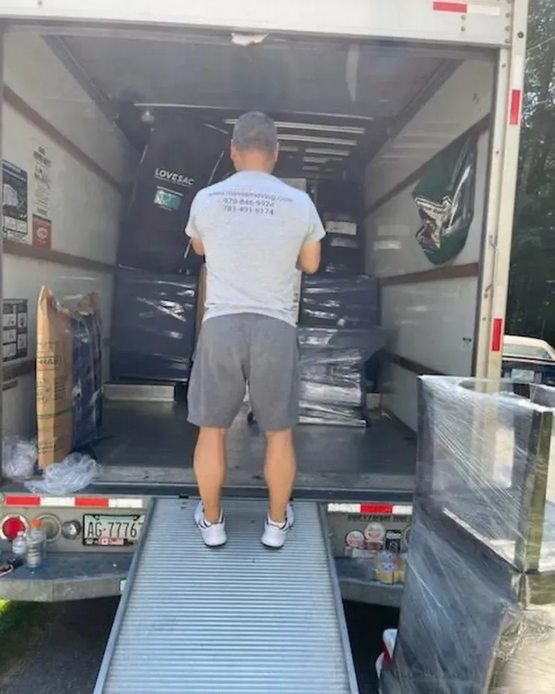 Man standing in the back of a moving truck, supervising the loading of furniture.