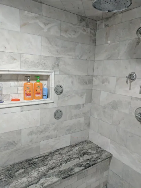 A bathroom with a shower and a bench.