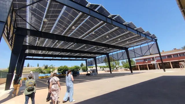 Elevated solar pergola canopy shading a paved outdoor courtyard.