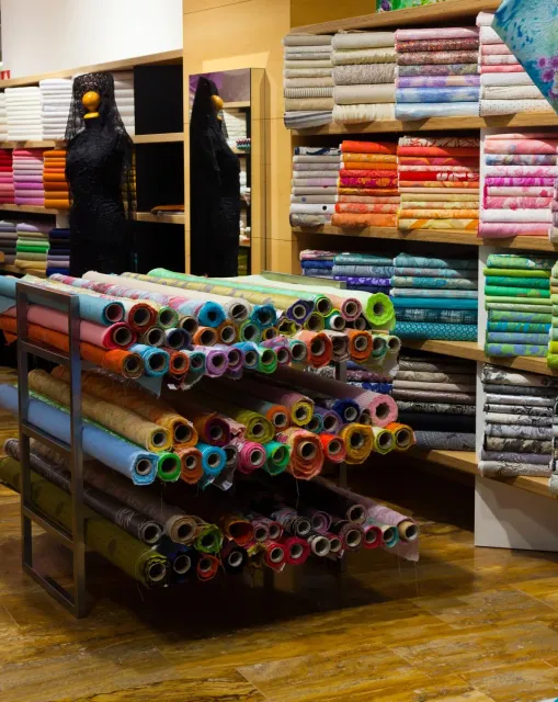 A store filled with rolls of fabric and a mannequin.