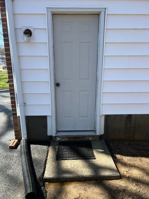 A white door is on the side of a white house.