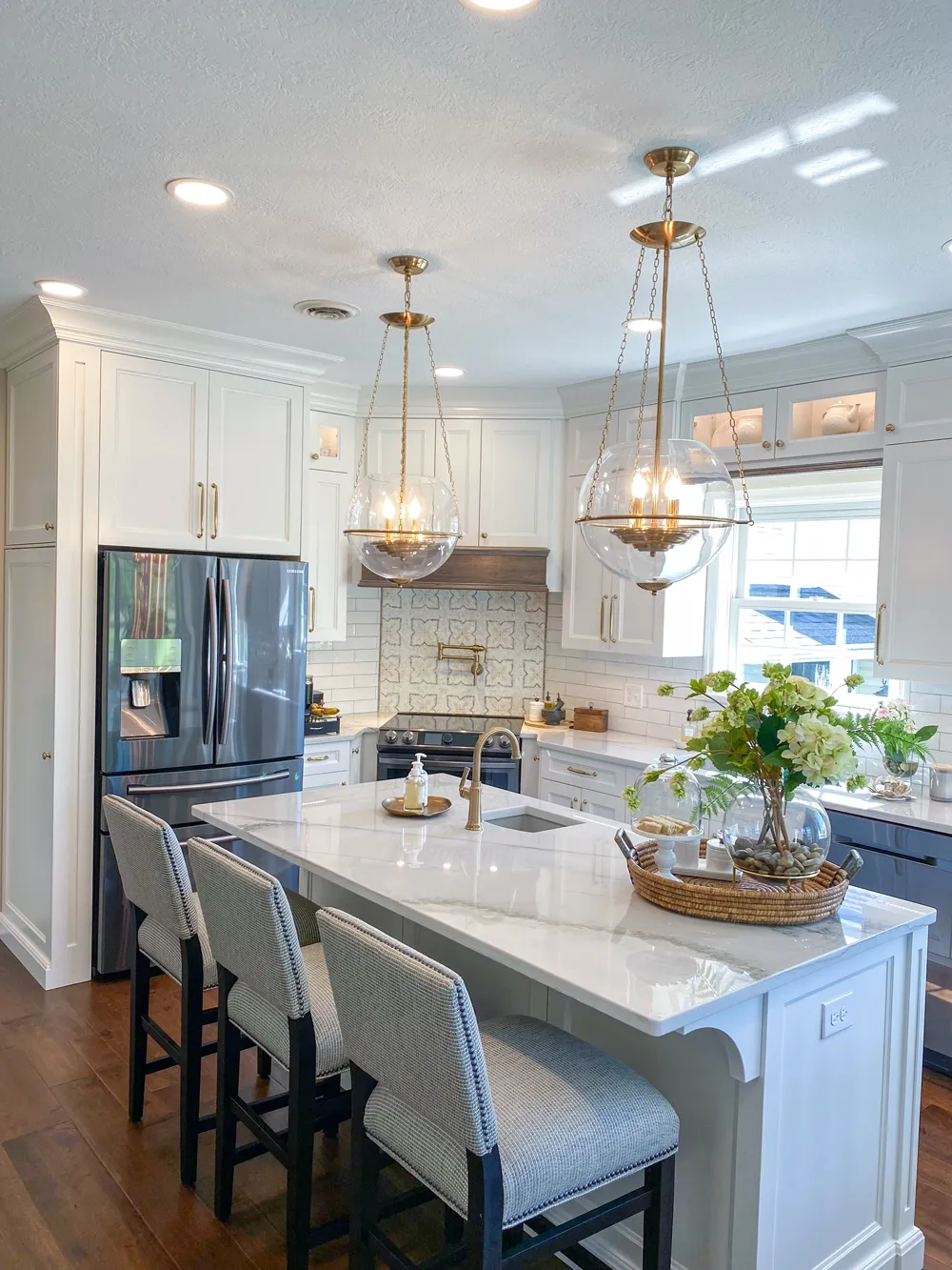 Haute Designs Kitchen & Bath. Quartzite countertop. Gold Top Knobs hardware. Gold Brizo faucet. Marble mosaic feature wall. Organizational accessories. Kitchen Island with seating