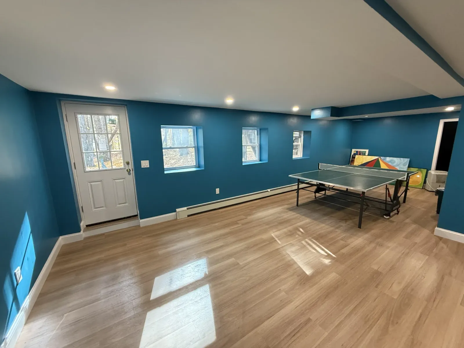 Sudbury basement renovation featuring a ping pong table area, bright blue paint, and recessed lighting.