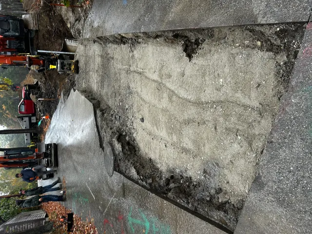 Excavator removing concrete pad debris with dump truck on active construction site