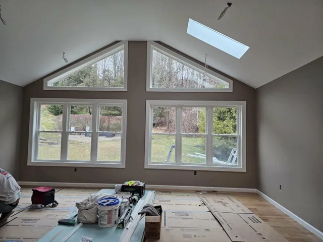 After: the same vaulted wall smooth and painted, with gable windows and a skylight