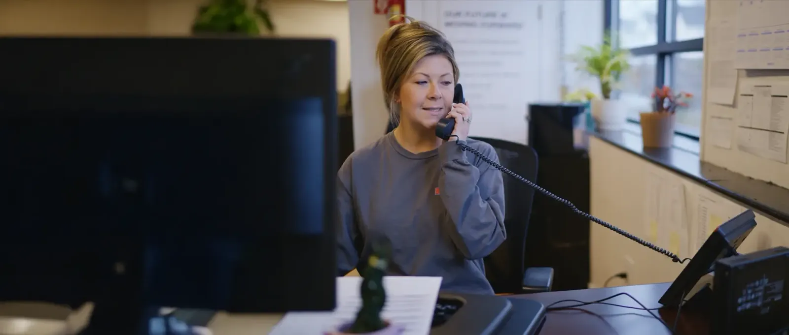 A Door Systems receptionnist sits at a desk on the phone.