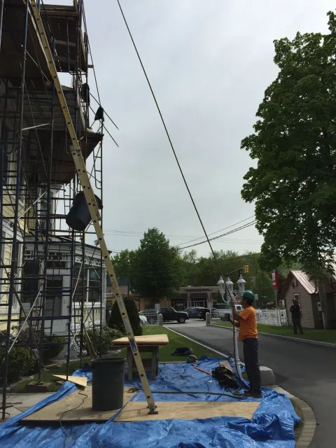A man is standing on a blue tarp in front of a building under construction