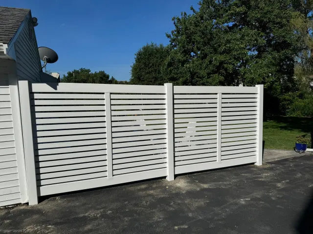 A white fence is sitting in front of a house