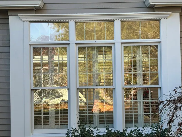 Historic window installation showcasing energy-efficient double-pane design with muntin patterns, surrounded by modern siding in Hanover, MA.