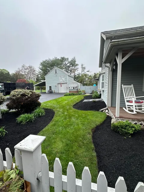 Clean weed-free black mulch bed along the front of a house