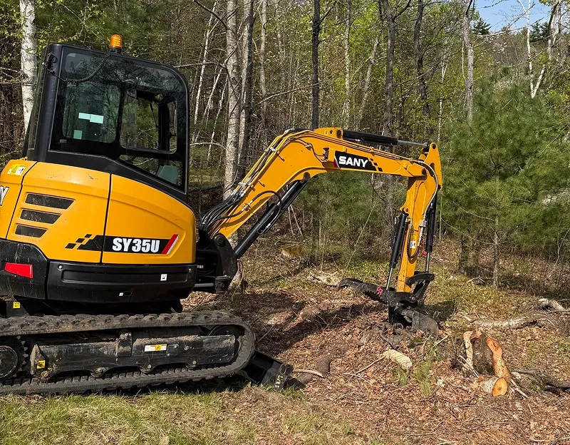 Yellow excavator clearing forest area