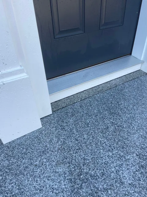 Front entrance with a dark door, white trim, and a speckled gray stoop.