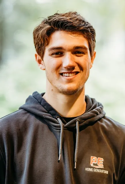 Man wearing a PE Home Generators hoodie, smiling.